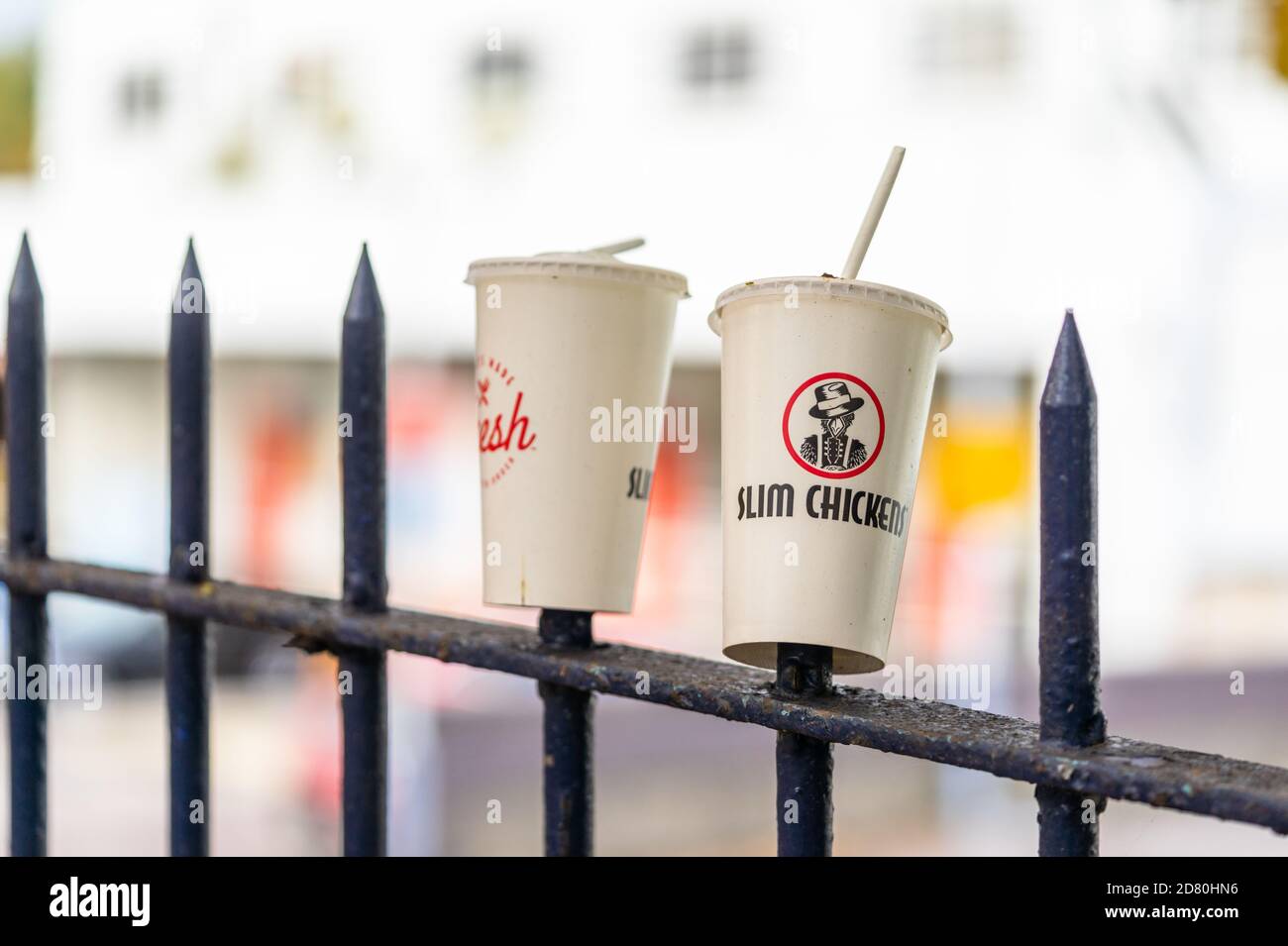 Discarded Slim Chickens fast food paper cup litter/ trash on an iron fence in Southampton, England, UK Stock Photo