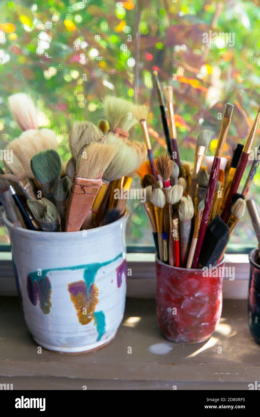 artists brushes in containers on a window sill Stock Photo
