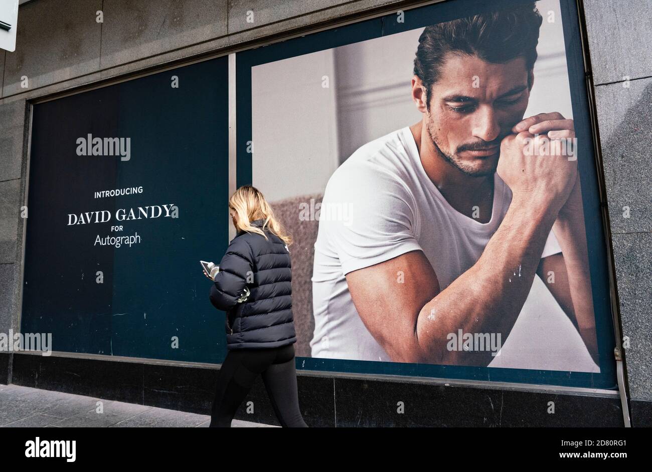 Glasgow, Scotland, UK. 26 October 2020. View of Glasgow city centre on weekday during circuit breaker lockdown with bars and restaurants closed. Pictured; Woman walks past billboard of David Gandy on Marks & Spencer store . Iain Masterton/Alamy Live News Stock Photo
