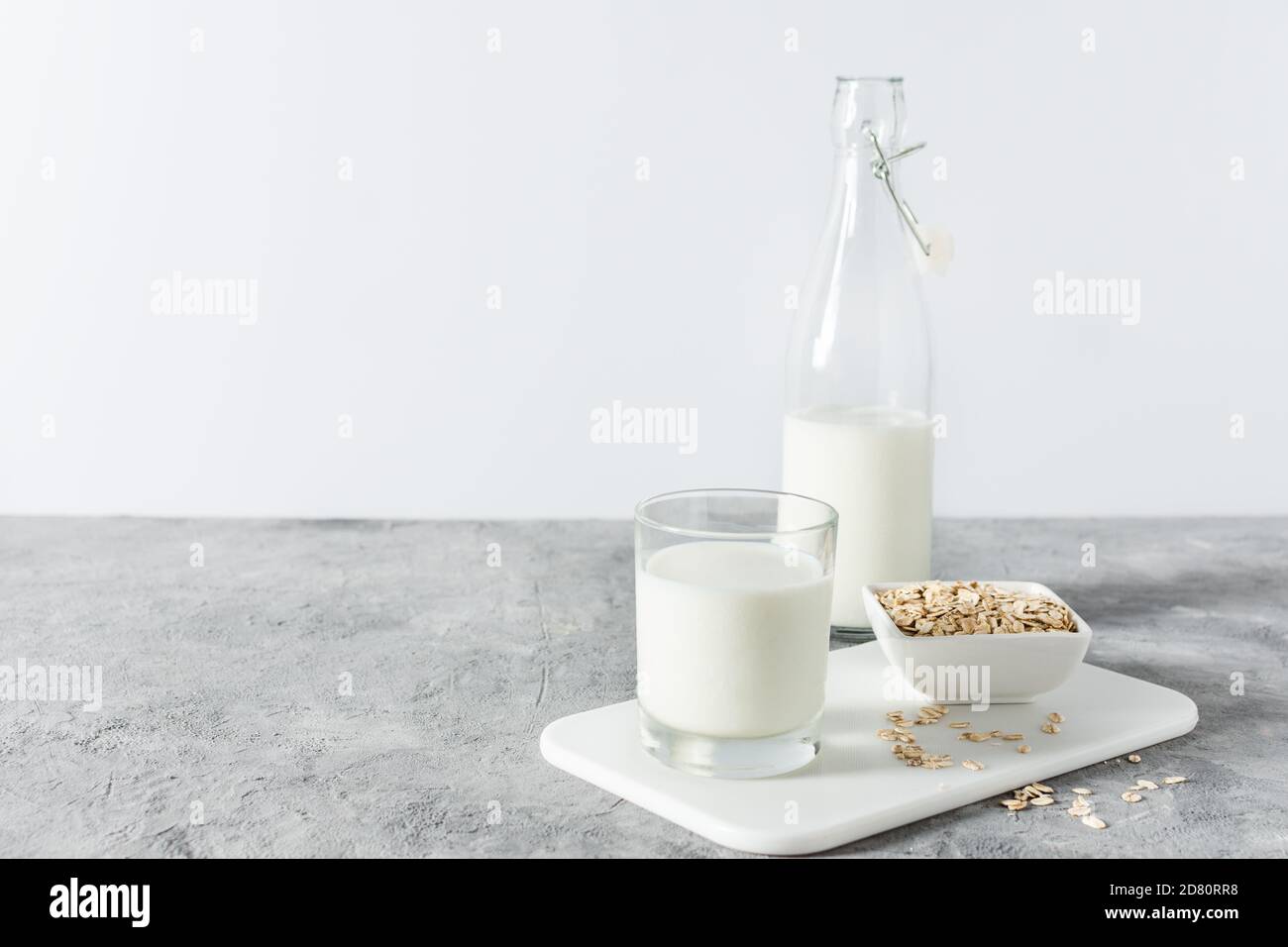 Homemade non dairy alternative milk made from oat flakes. Vegan oat milk on grey concrete table. Stock Photo