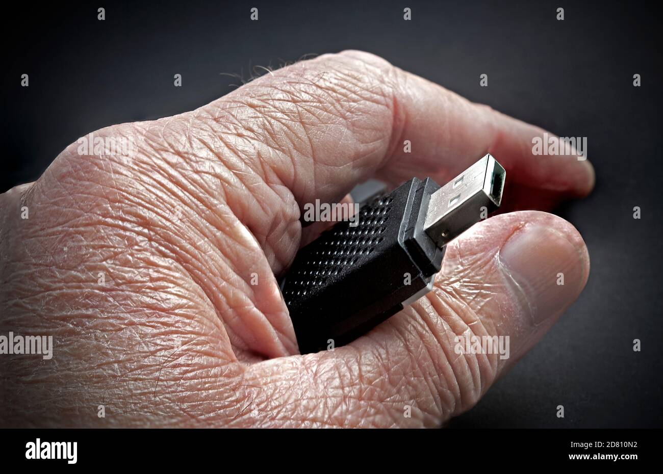 Elderly hand with wrinkles holding memory stick Stock Photo
