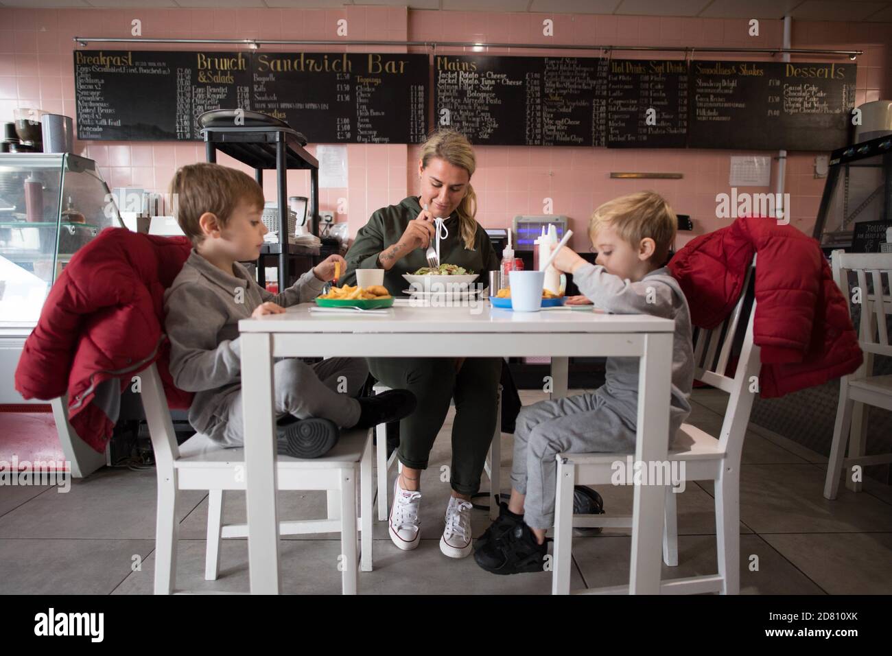 RETRANSMITTING ADDING NAMES Leigh Anderson, with her sons Charlie Brown (left) and Albie Brown, eat a meal at the Kitchen cafe in Bermondsey, London, are providing free school meals for children over the half term holidays. Local councils and businesses are continuing to pledge free food for children in need during this week's half term break after the Government defeated a Labour motion to extend free school meals provision in England over the holidays. Stock Photo