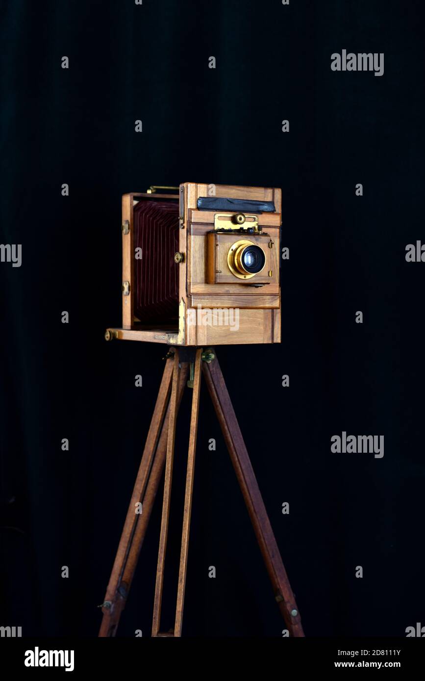 Antique Full Plate Studio Camera in Mahogany Wood with Brass Fittings Shoot on Black Background with Vintage Wooden Tripod Stock Photo