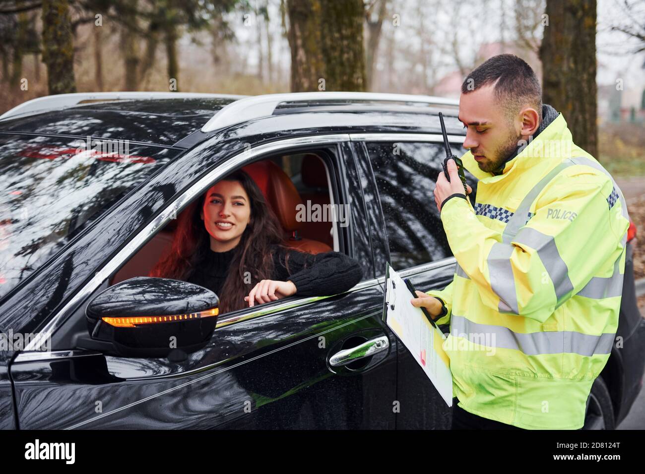 Male police officer in green uniform talking by radio transmitter near