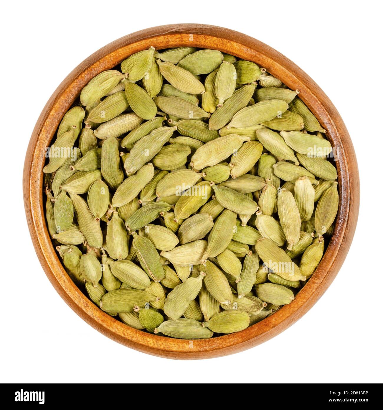 Green cardamom pods in a wooden bowl. True cardamom, processed pods and seeds of Elettaria cardamomum, sometimes cardamon or cardamum, used as a spice Stock Photo