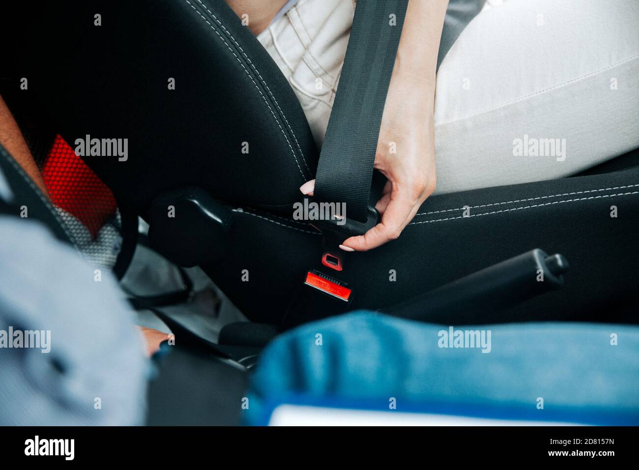 Female hand fastens seat belt. Close-up cut view of woman in white jeans  holding black seatbelt. Road traffic safety concept. Conscious driving  concep Stock Photo - Alamy