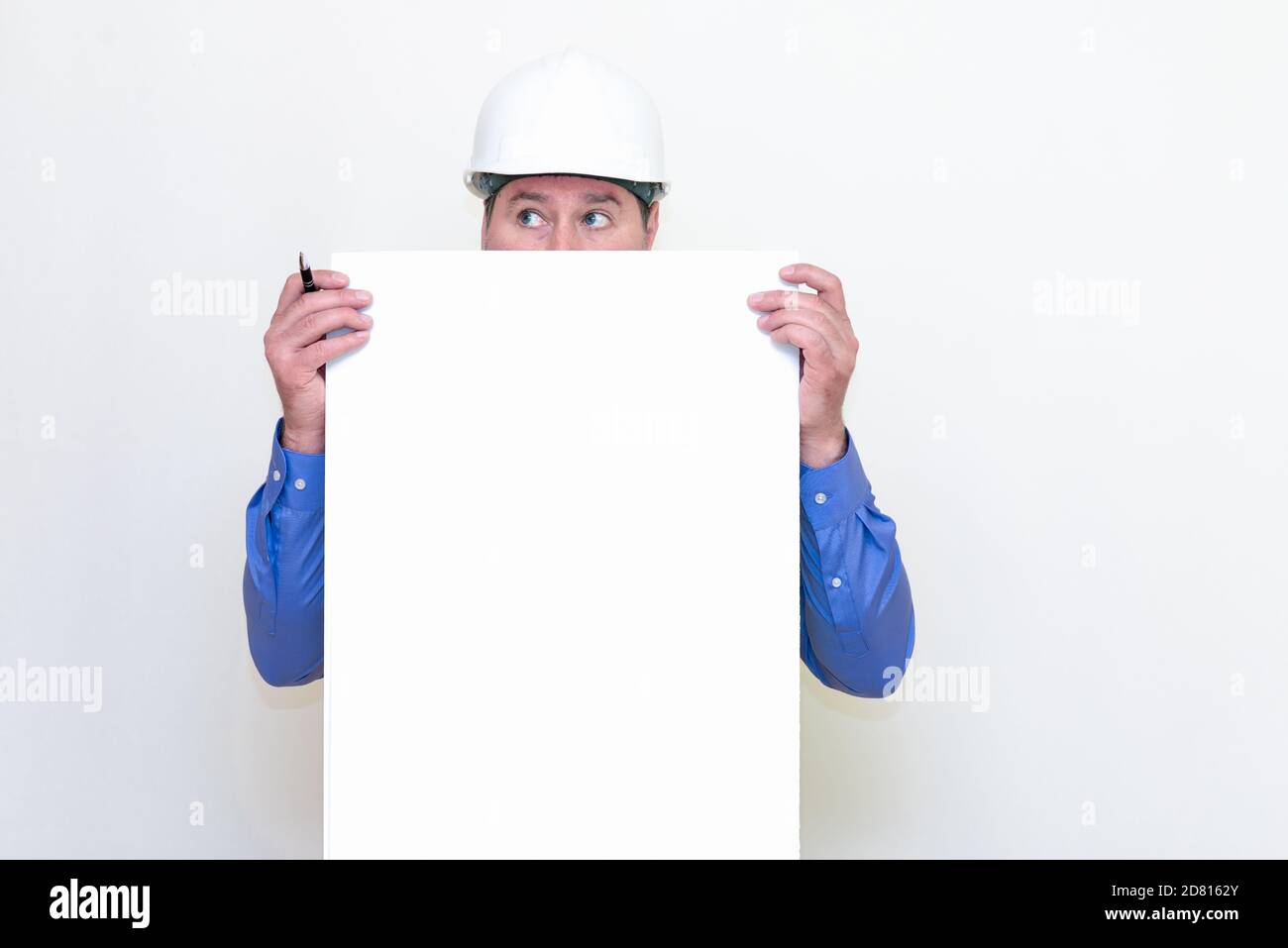 Close-up Engineer man wearing a helmet and reflector vest, standing and holding a billboard. White background. Stock Photo