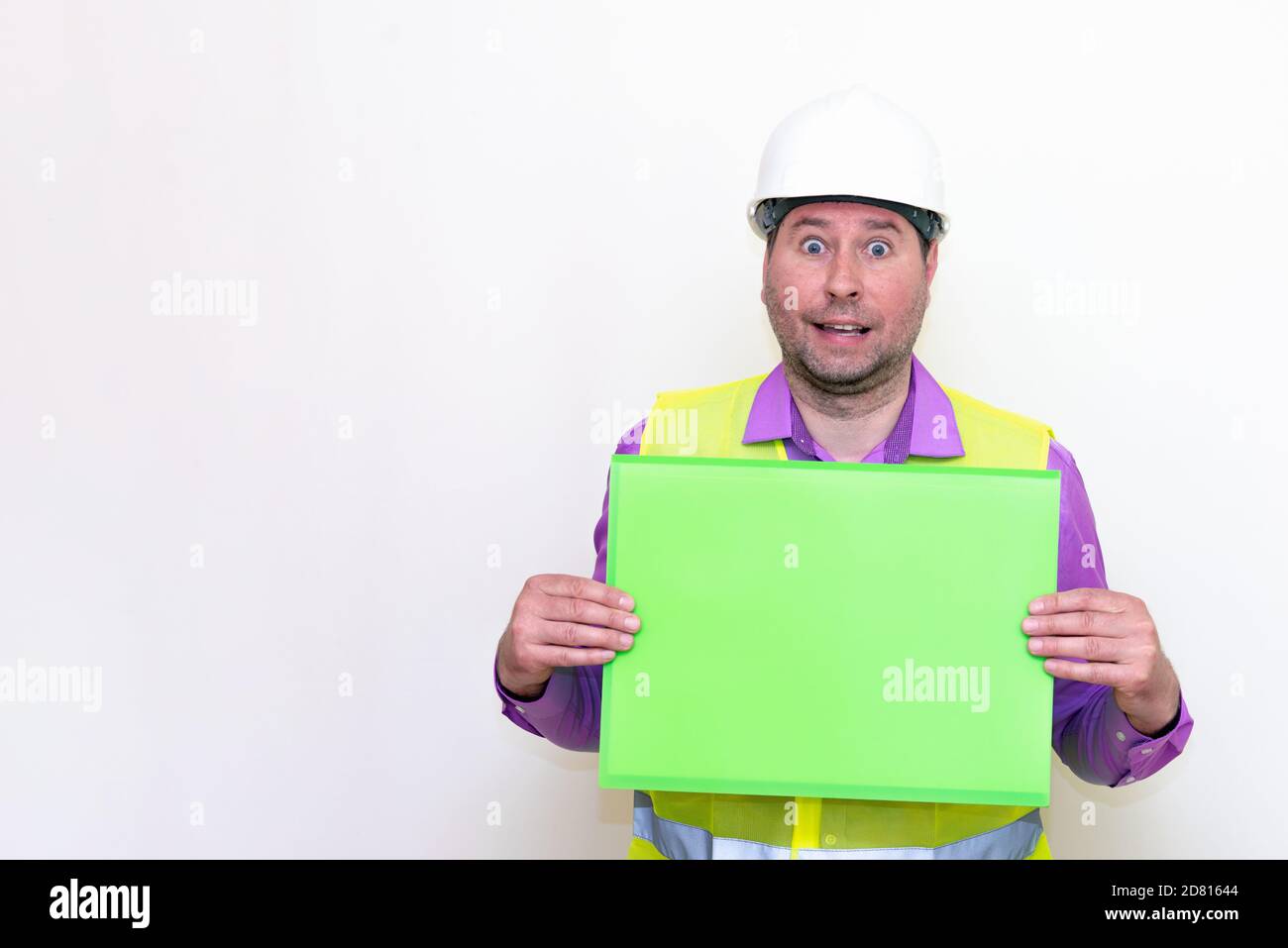 curious surprised architect in a construction helmet holding a folder, free place mock up banner.Studio shoot. Stock Photo