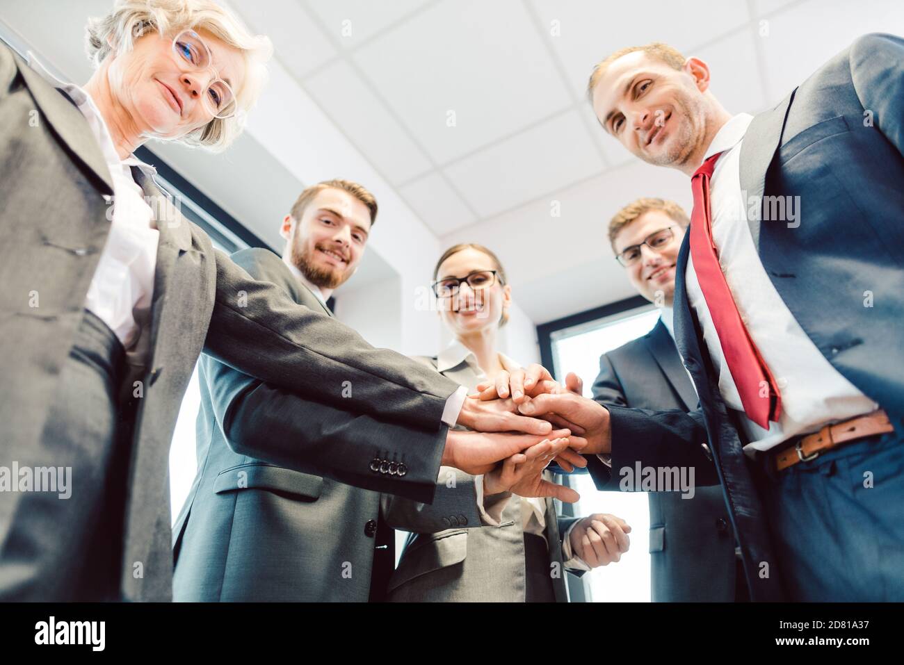 Business Team stacking hands looking at camera Stock Photo - Alamy