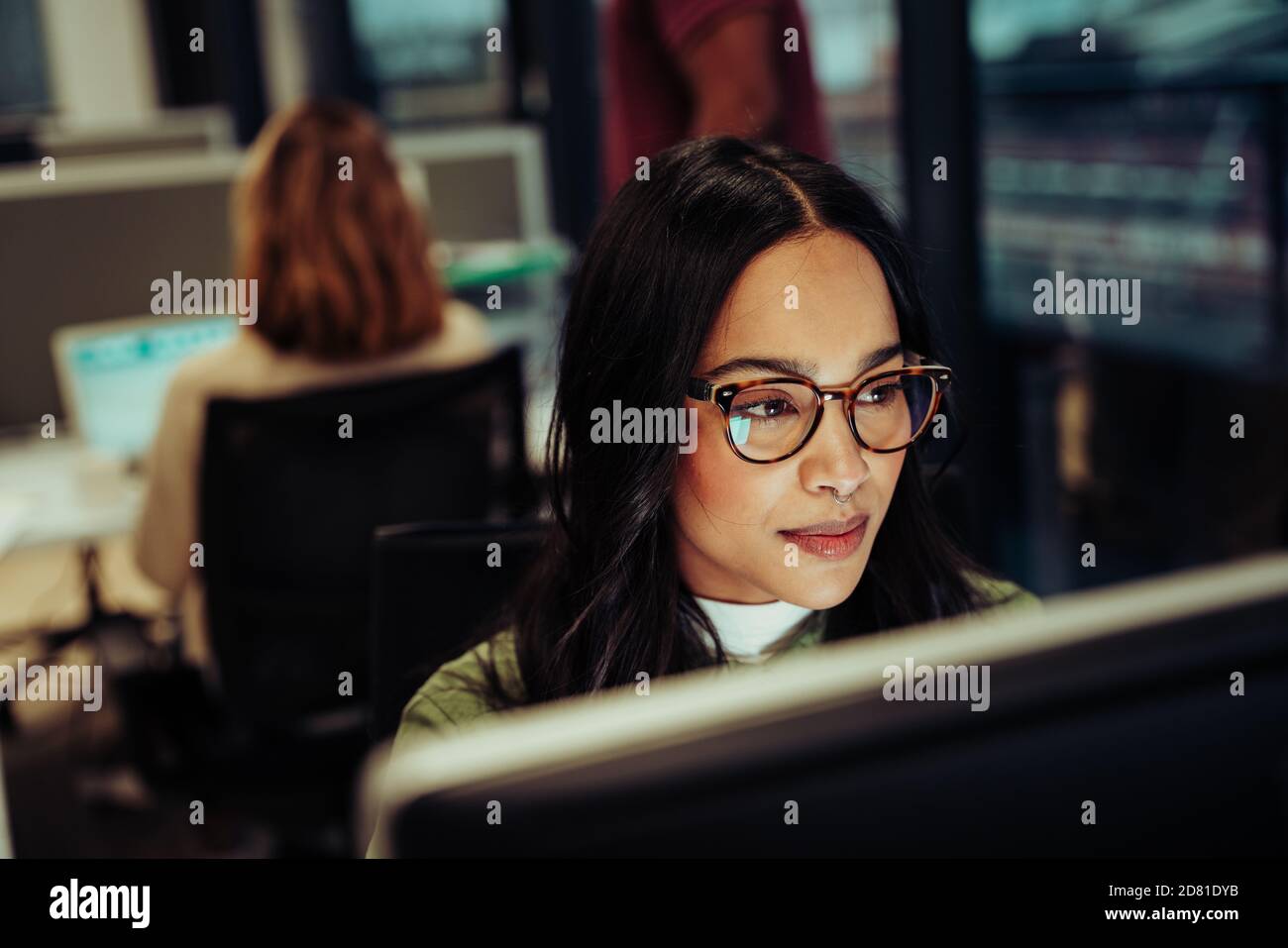 Portrait of mixed race woman working on business report typing on desktop sitting in office block Stock Photo