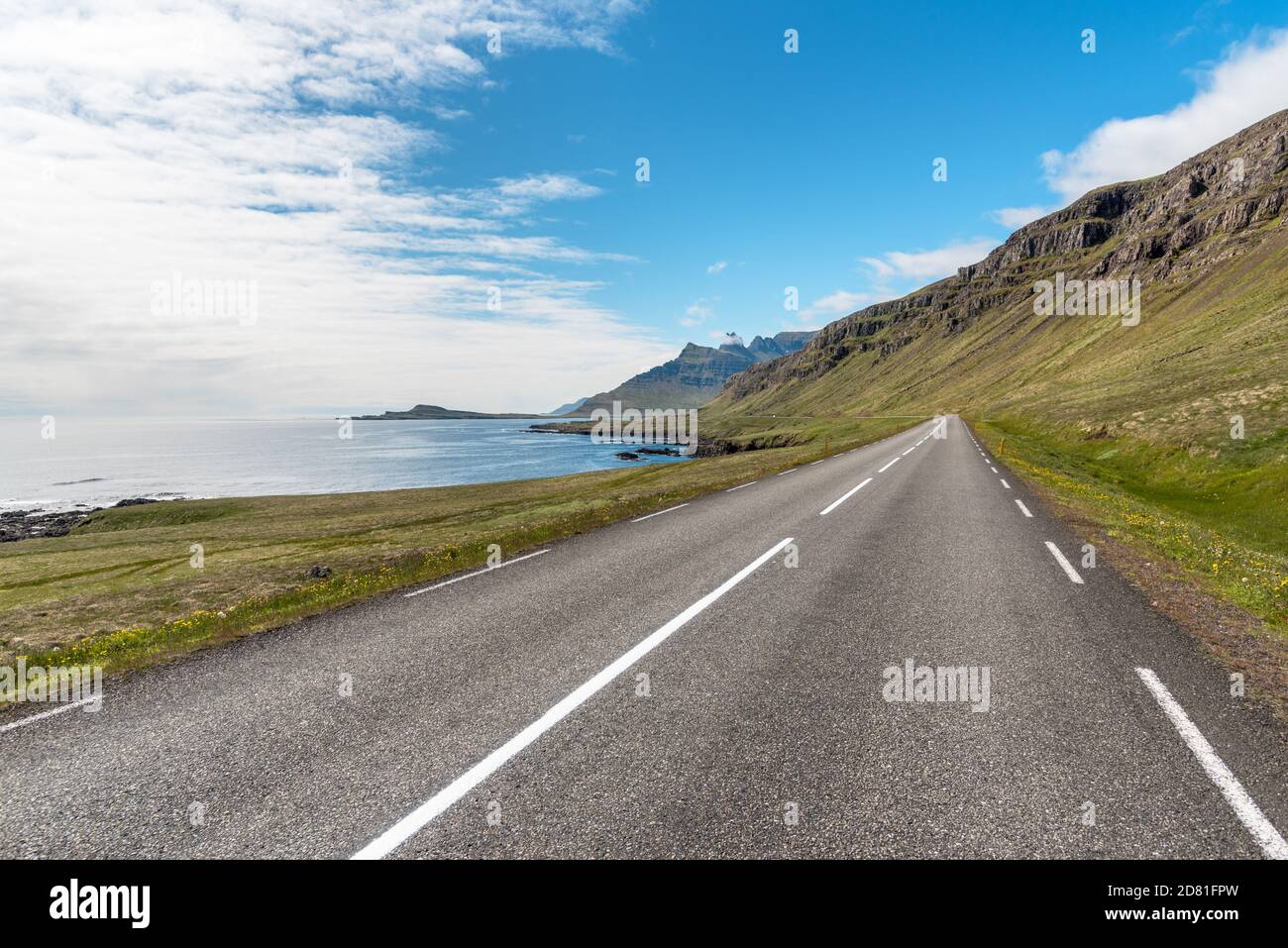 Straigh stretch of a coastal road in Iceland and blue sky with clouds in summer Stock Photo