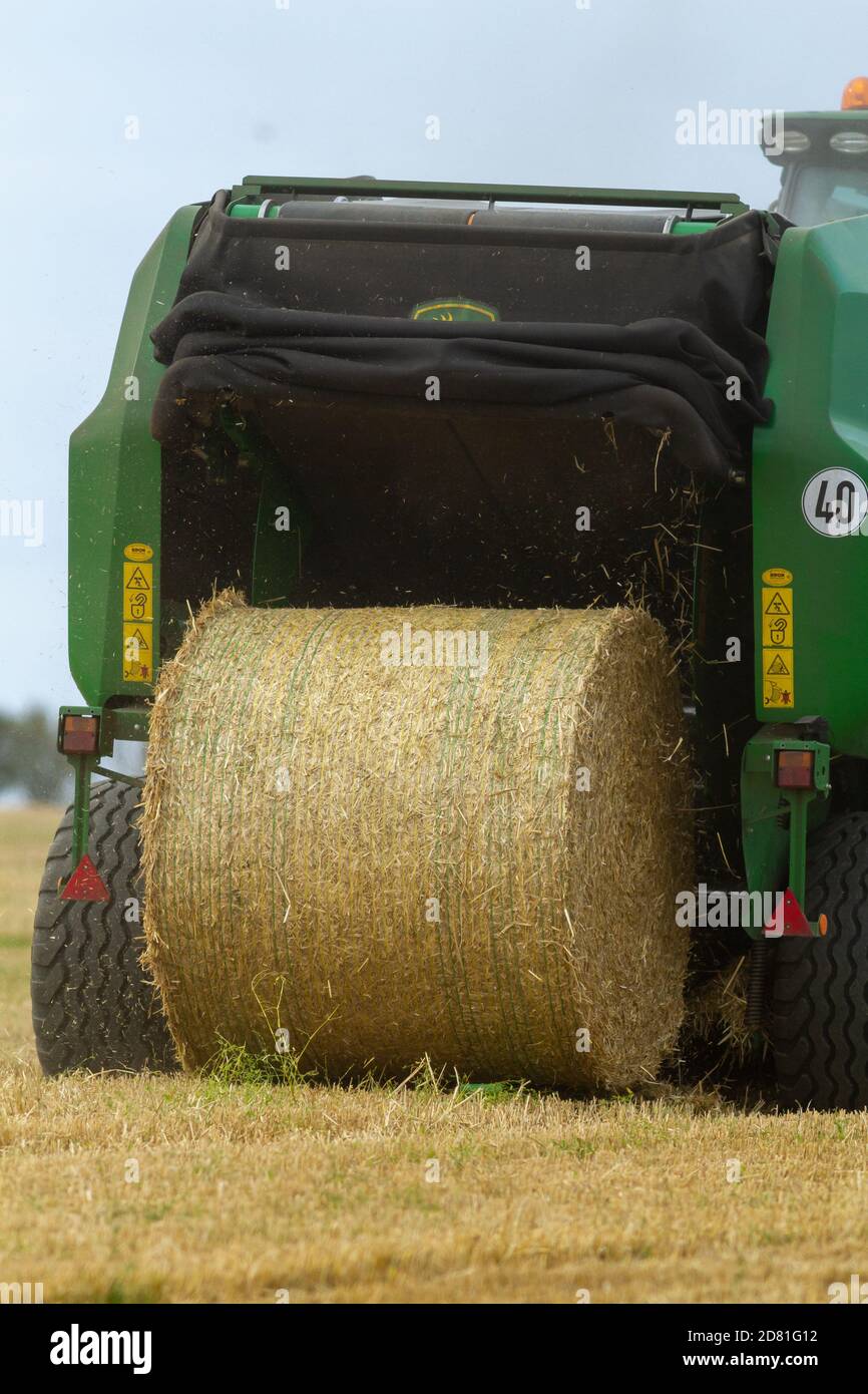 Close up of the back of a hay baling machine making cylindrical bales of hay, East Yorkshire, UK Stock Photo