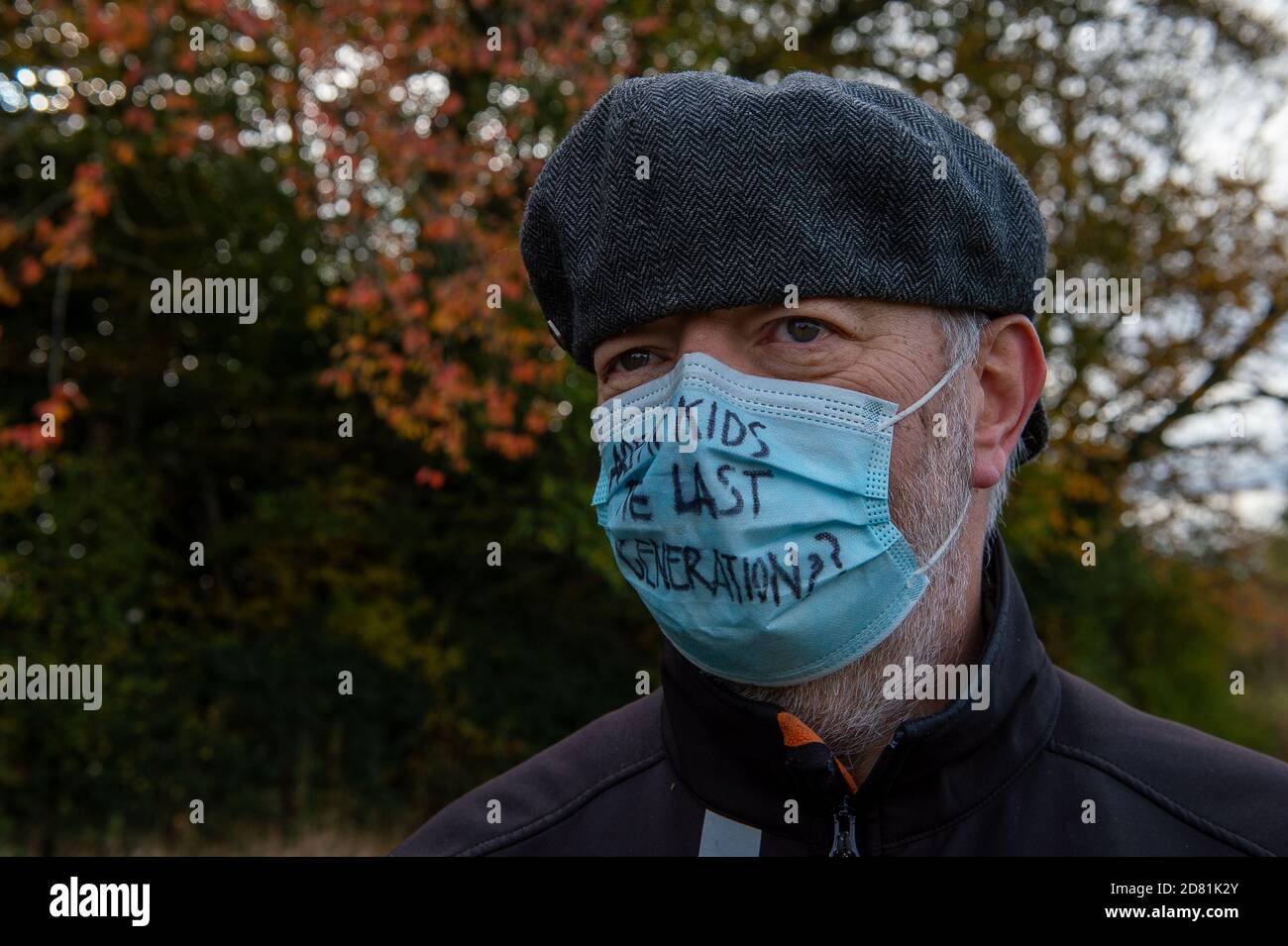 Aylesbury Vale, Buckinghamshire, UK. 26th October, 2020. A protester wears an are out kids the last generation facemask. HS2 are continuing to fell ancient woodland at Grim's Ditch in Buckinghamshire this morning. Anti HS2 environmental campaigners allege that HS2 do not have a bat licence for felling in these ancient woodlands and so are potentially committing a wildlife crime. They have reported the matter to the Police again this morning an are awaiting a response. Construction of the High Speed Rail from London to Birmingham puts 108 ancient woodlands, 33 SSSIs and 693 wildlife sites at ri Stock Photo