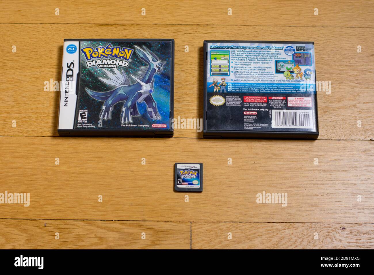 A Pokemon Diamond Cartridge and The Front and Back of It's Game Case for the Nintendo DS on a wood floor. Stock Photo