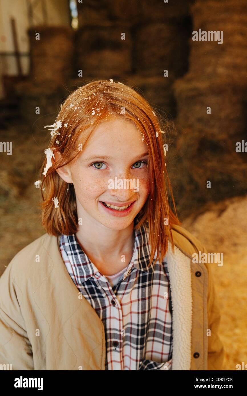 Funny ginger girl with wood shavings on her hair inside big barn Stock  Photo - Alamy