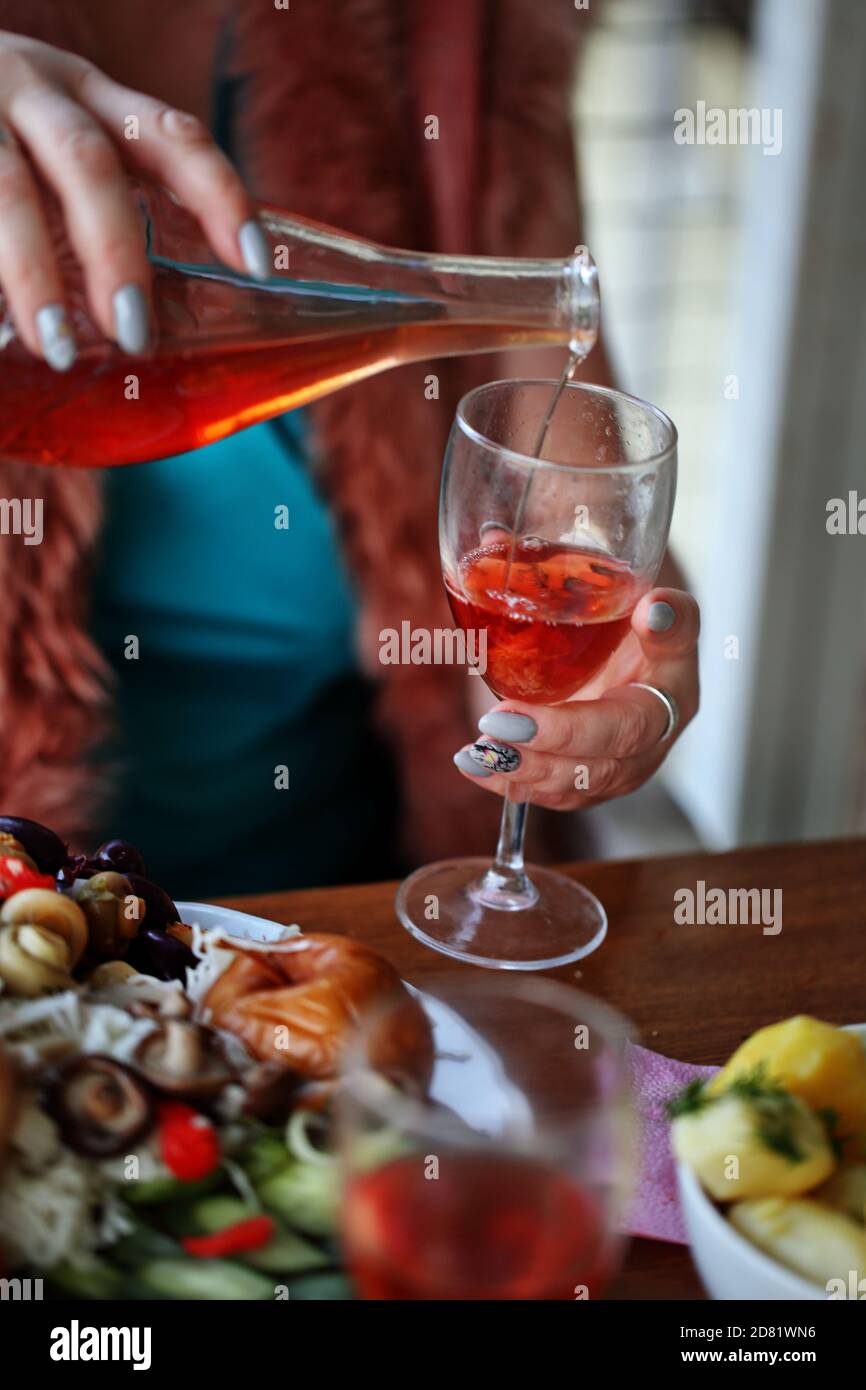 Woman's hand pours red wine from a bottle into a glass Stock Photo - Alamy