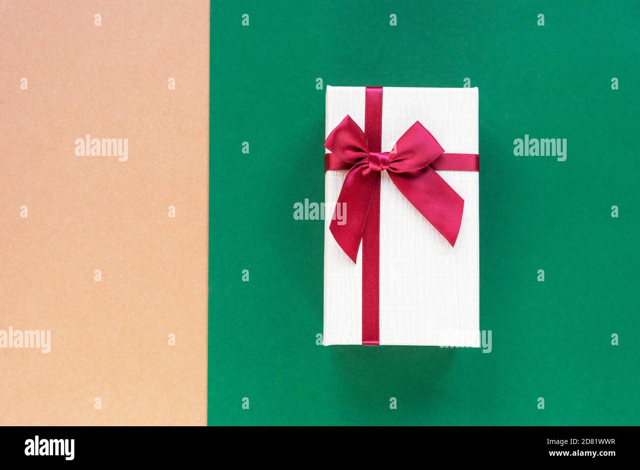 Gift in a box on beige and green combo background. Holiday concept. Top view, flat lay, copy space. Stock Photo