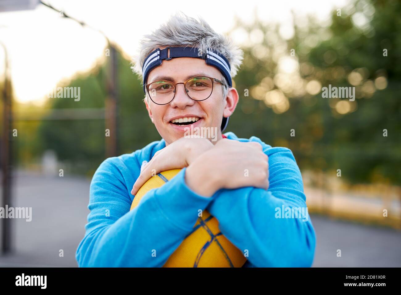 young caucasian teen boy playing basketball, handsome guy in casual sportswear alone at basketball playground, practice Stock Photo