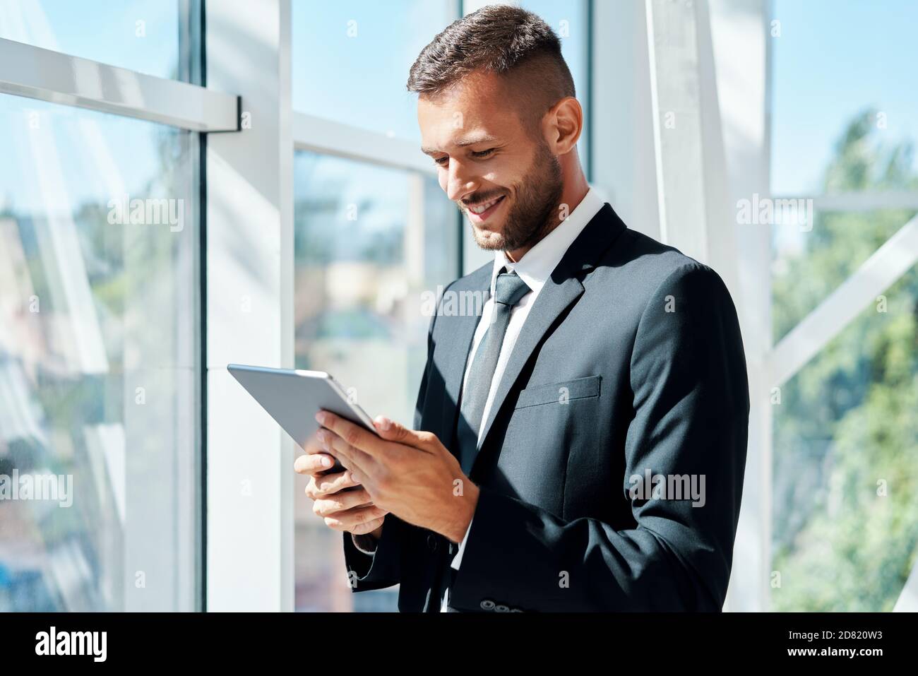 Young smiling businessman working on tablet in modern creative office ...