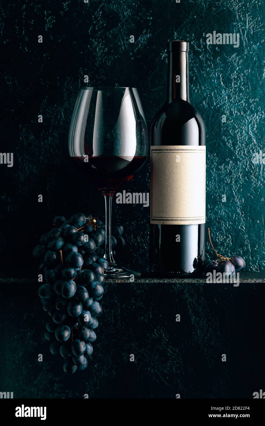 Red wine and blue grapes on an old dark blue background. On a bottle
