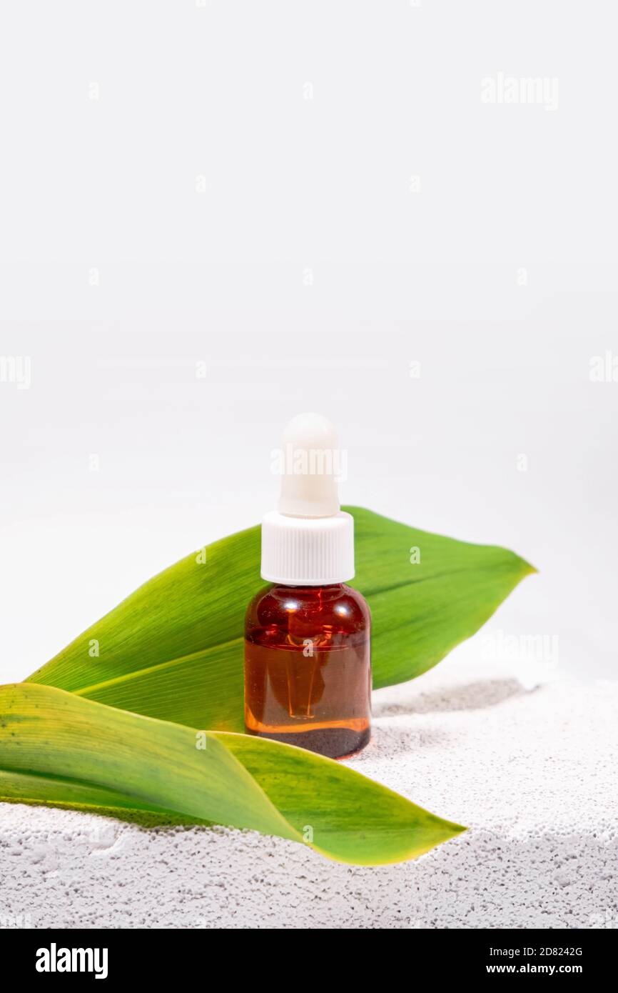 Natural cosmetology background. A glass dropper bottle with a pippette on eco materials like cement, leaf, cross section of the tree Stock Photo