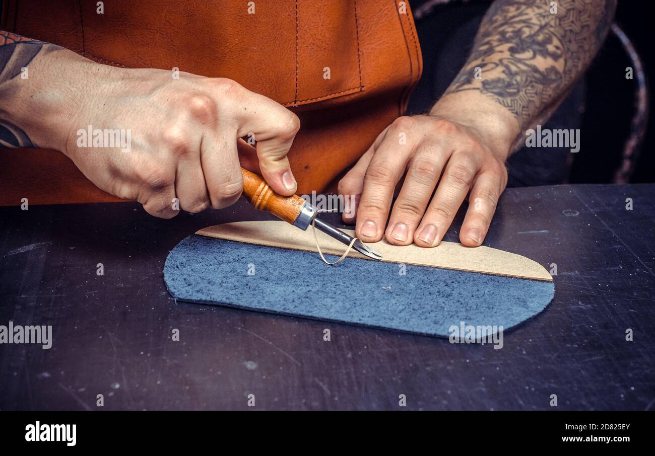 Artisan performing leatherwork on a new product piece Stock Photo