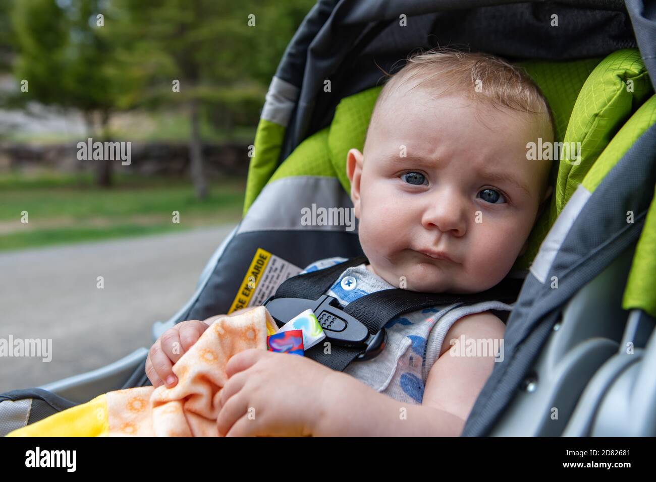 Portrait of cute little baby boy sitting in modern pram, with seatbelt