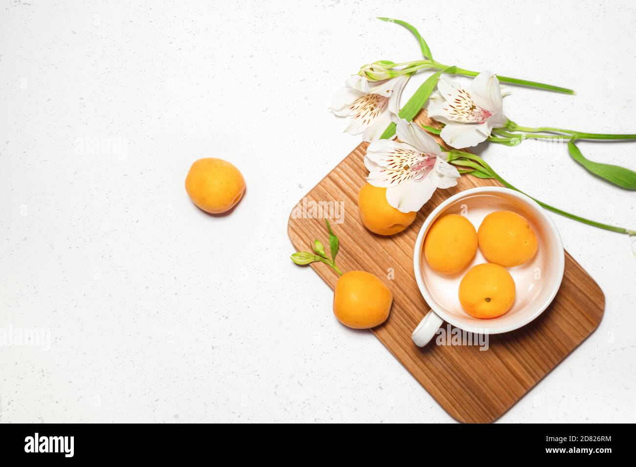 Apricot composition with wooden desk, white flowers on white concrete background. Culinary web banner. Flatlay. Space for text. Place for text Stock Photo