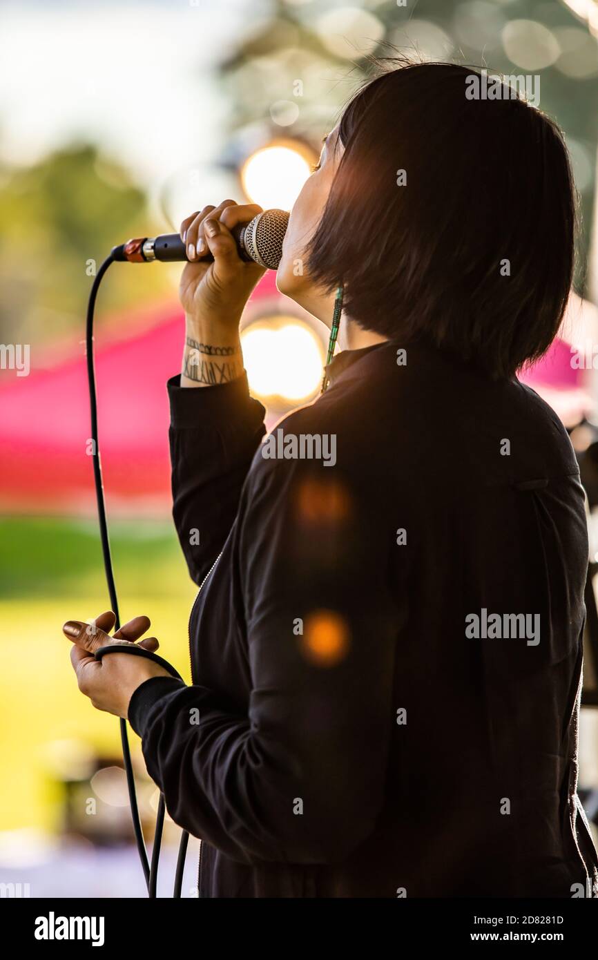 Outaouais, Quebec - September 19, 2020: Rear view of beautiful young woman holding mic while singing and performing in cultural fiesta Stock Photo