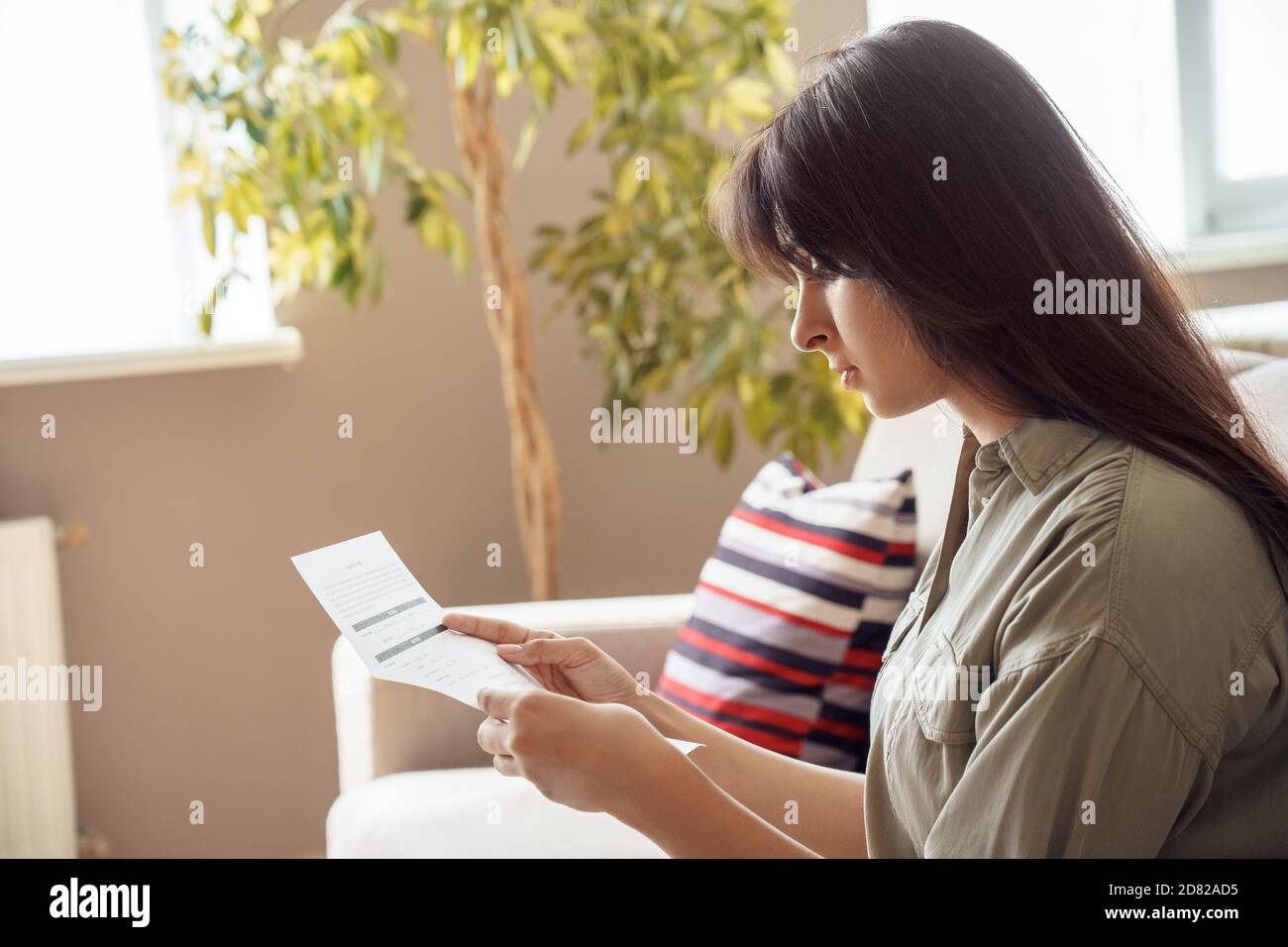 Young indian woman holding letter invoice reading bill at home. Stock Photo