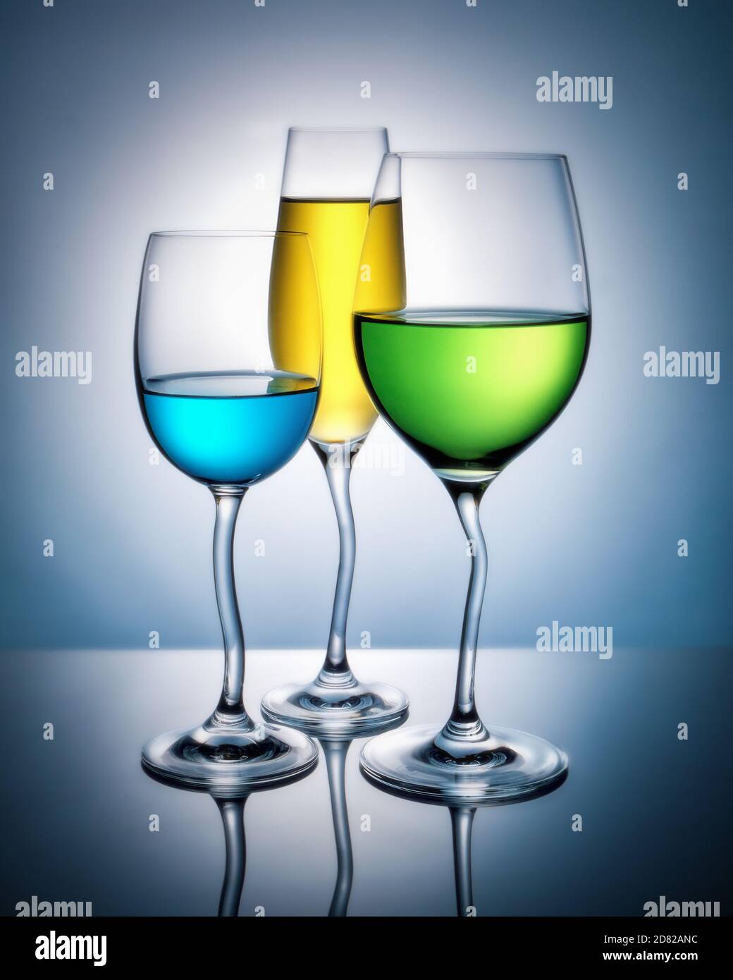 Wine glasses with colored liquid with reflection on a colored background. Stock Photo