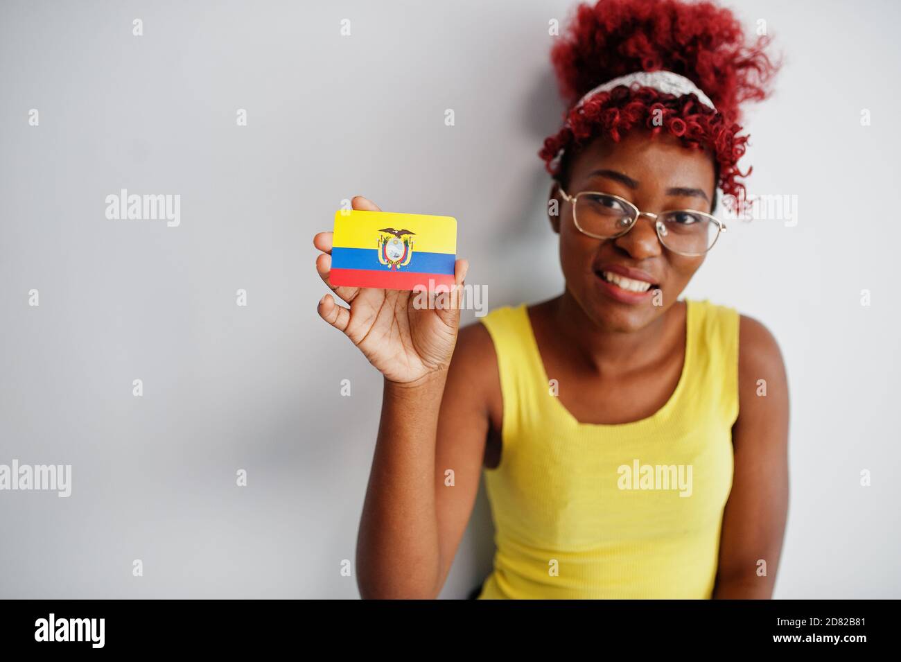 African american woman with afro hair, wear yellow singlet and eyeglasses, hold Ecuador flag isolated on white background. Stock Photo