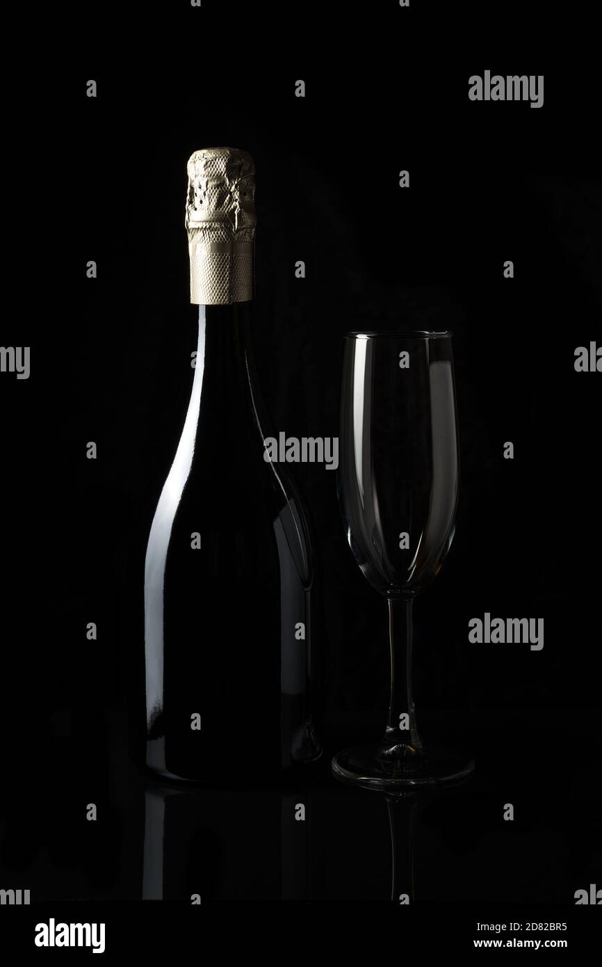 Sparkling wine with an empty glass on a dark background. Stock Photo