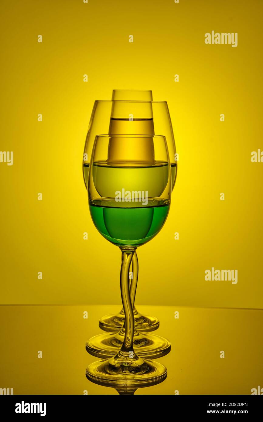 Wine glasses with colored liquid with reflection on a colored background. Stock Photo