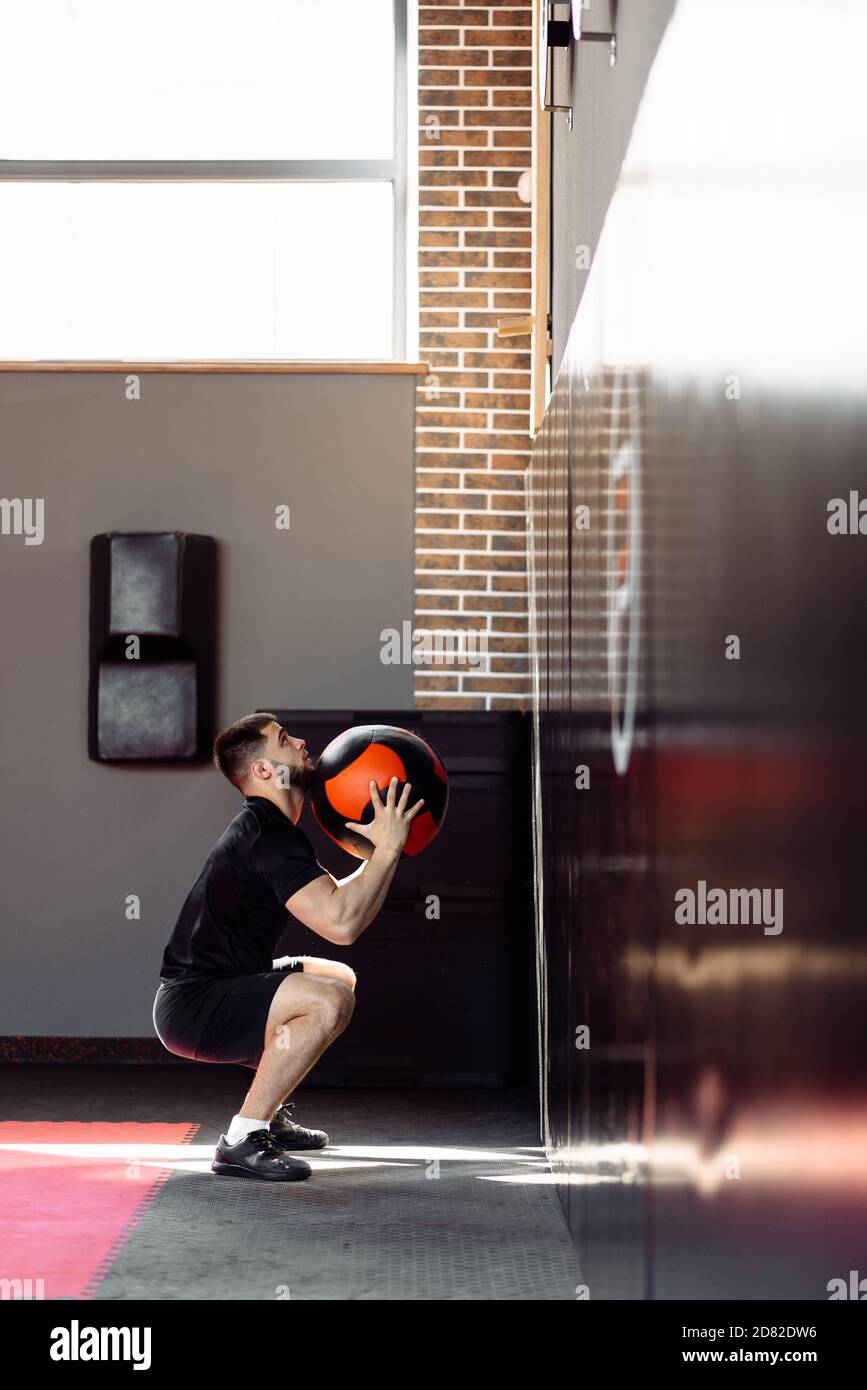Wall ball training. Young athlete doing wall ball exercise at gym