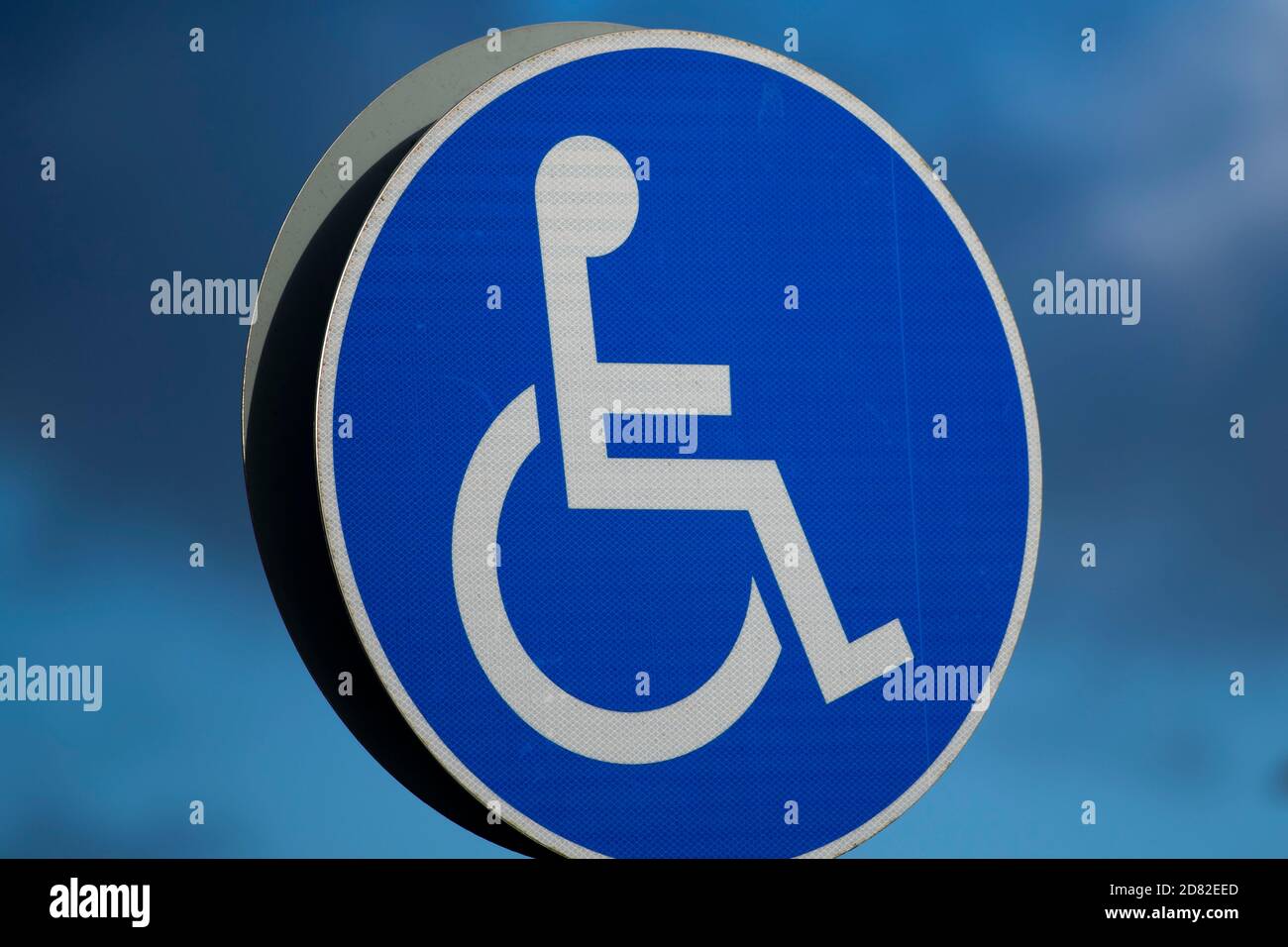 A disabled parking sign against a blue sky Stock Photo - Alamy