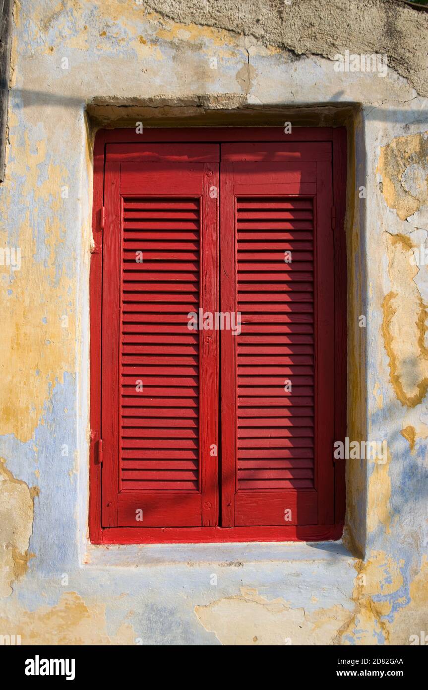 window with red shutter closed in neighborhood of Anafiotika in town of Athens Stock Photo