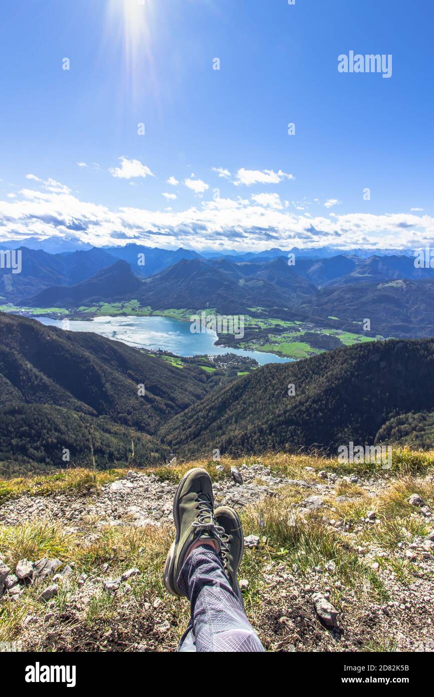 Legs of traveler sitting on a high mountain.Freedom wanderlust travel concept.Trekking boots against a beautiful landscape.Wonderful breathtaking view Stock Photo