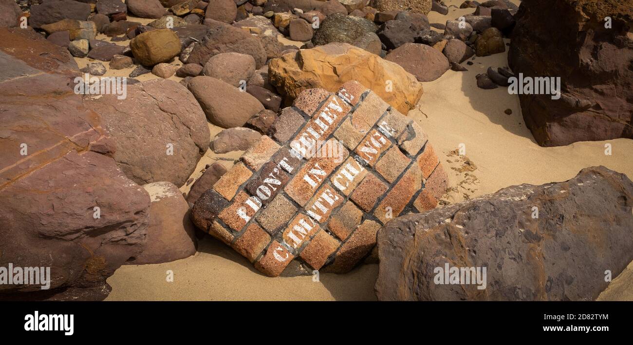 I don’t believe in climate change graffiti on old wall washed into the sea, coastal erosion and climate change Stock Photo