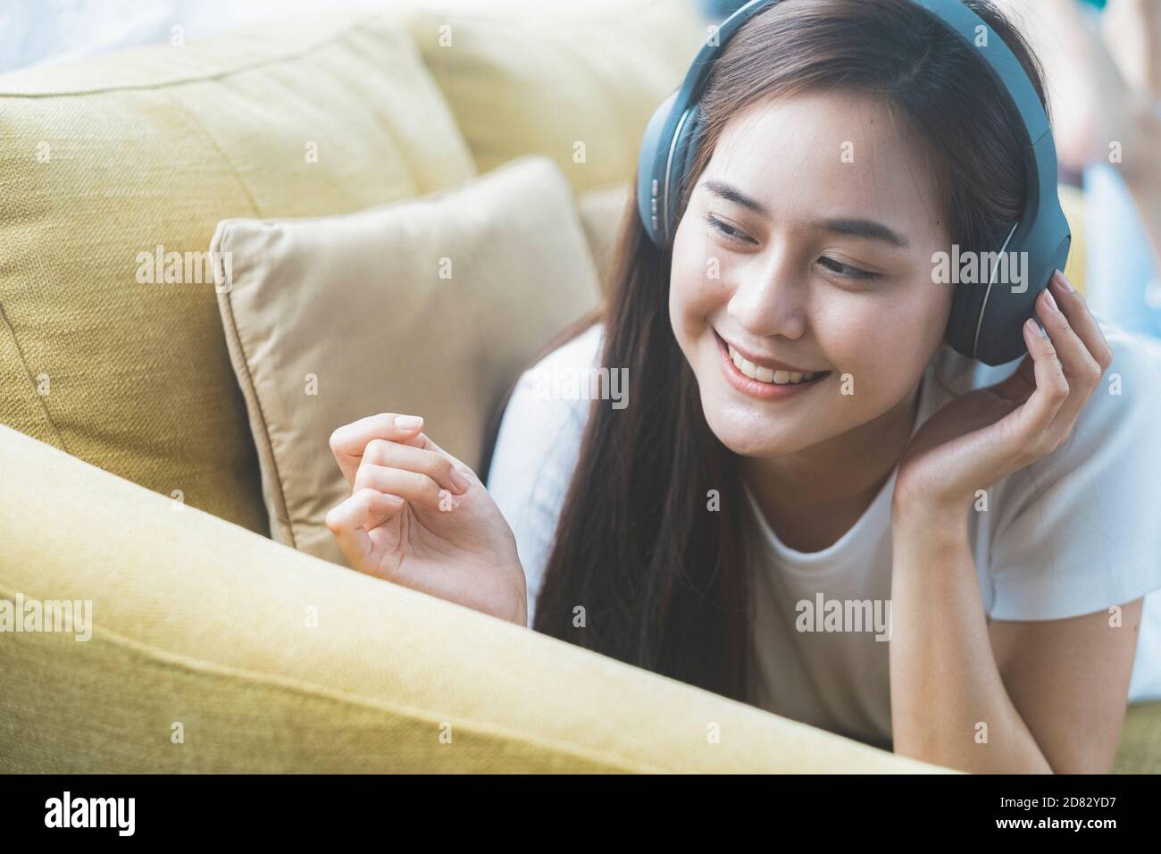 Young woman listening to music lying on sofa in room Stock Photo - Alamy