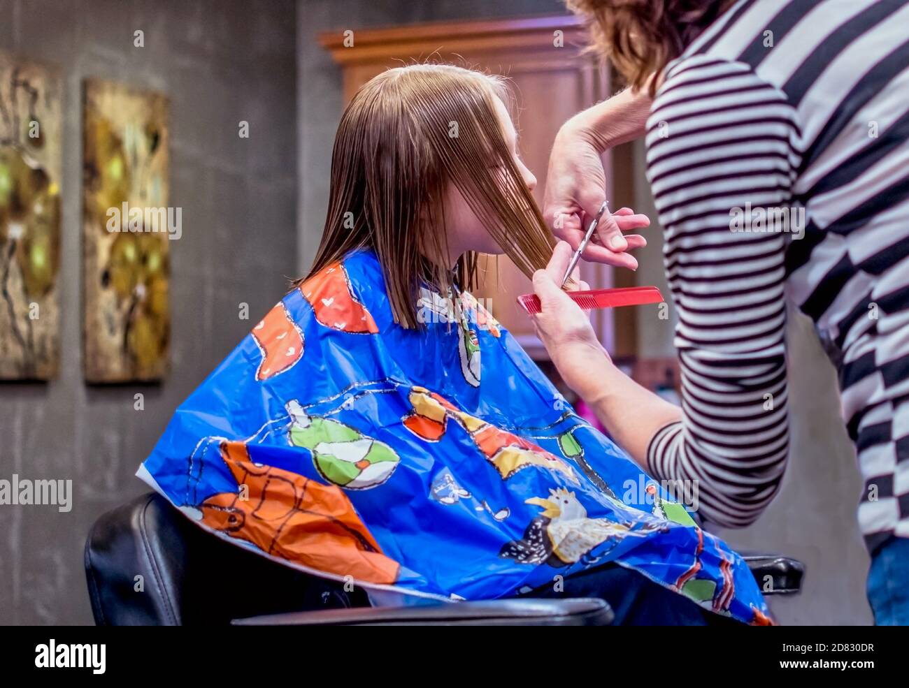 Young girl sits still as a stylist cuts her hair at a local beauty salon Stock Photo