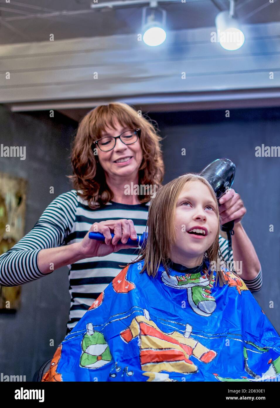 A young girl is happy as a beautician styles her just cut hair Stock Photo