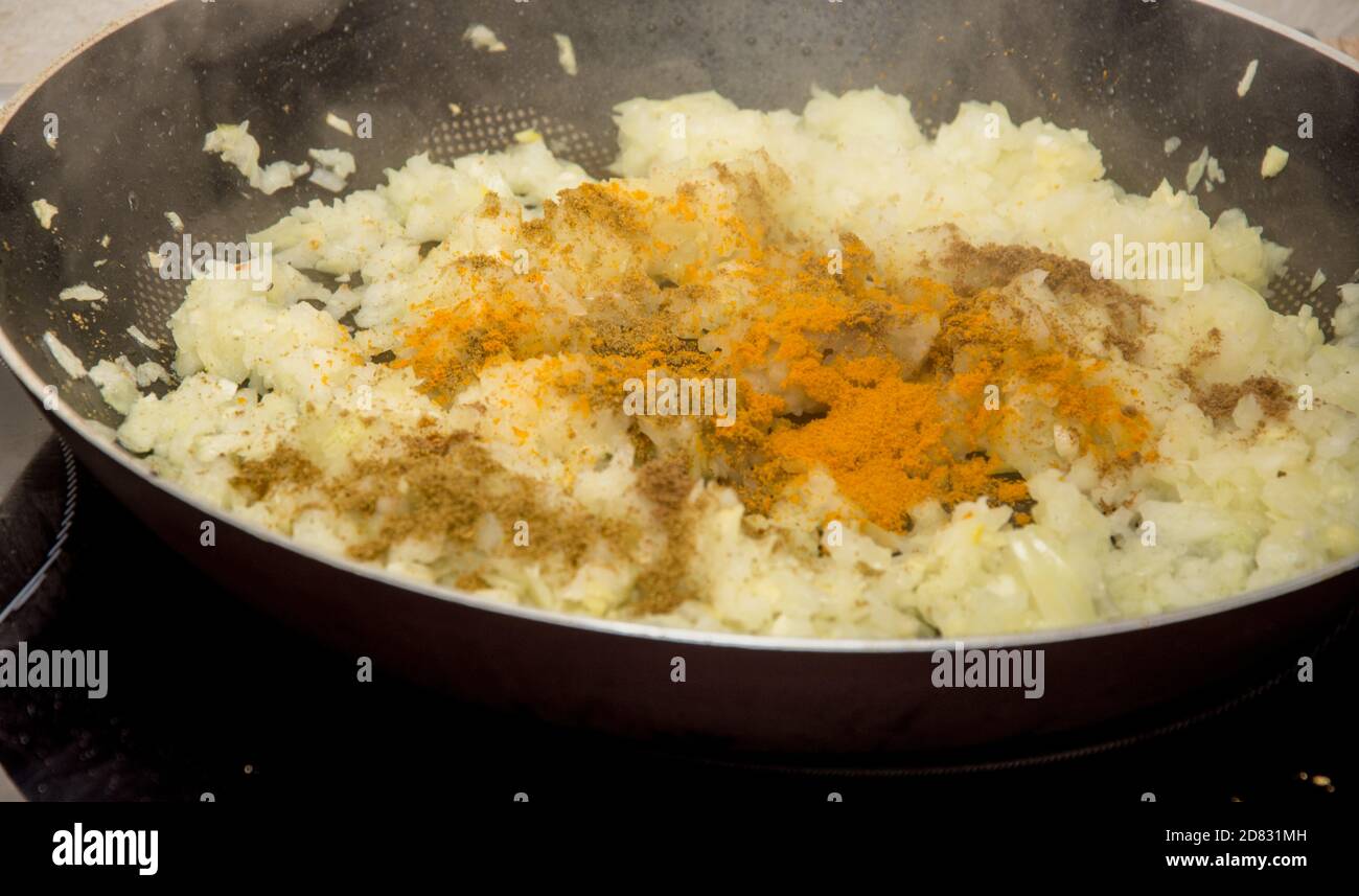 Frying golden onion with indian condiments and curry in the hot black