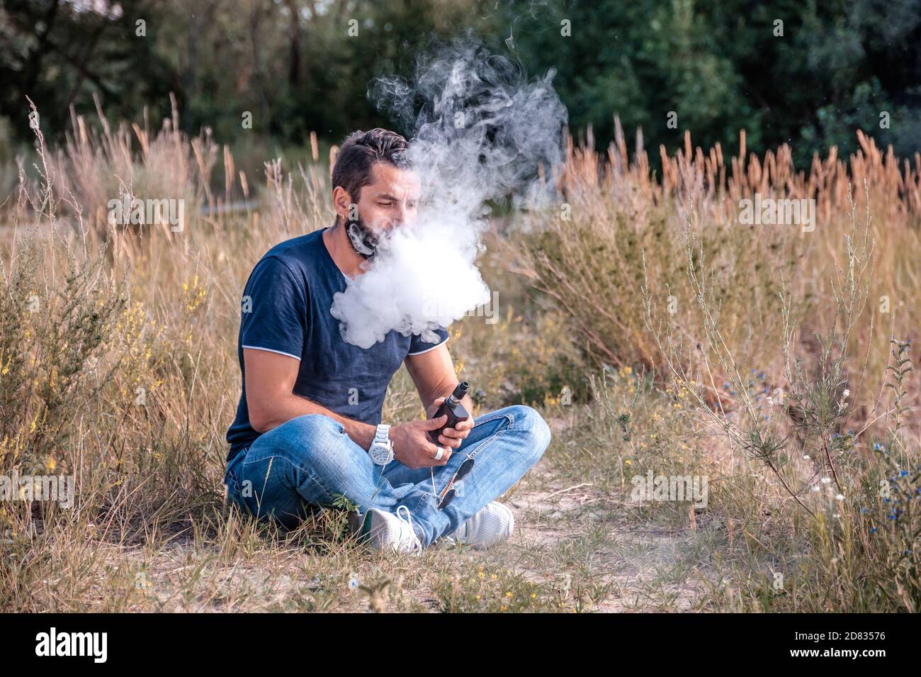 Brutal vaper with electronic smoke device on the grass of the forest. The man smokes Stock Photo - Alamy Brutal vaper with electronic smoke device on the grass of the forest. The man smokes Stock Photo - Alamy