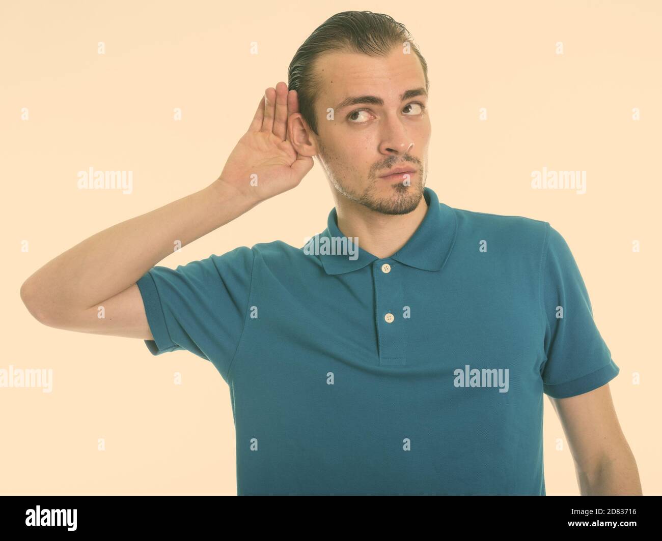 Studio shot of young bearded man listening while thinking against white