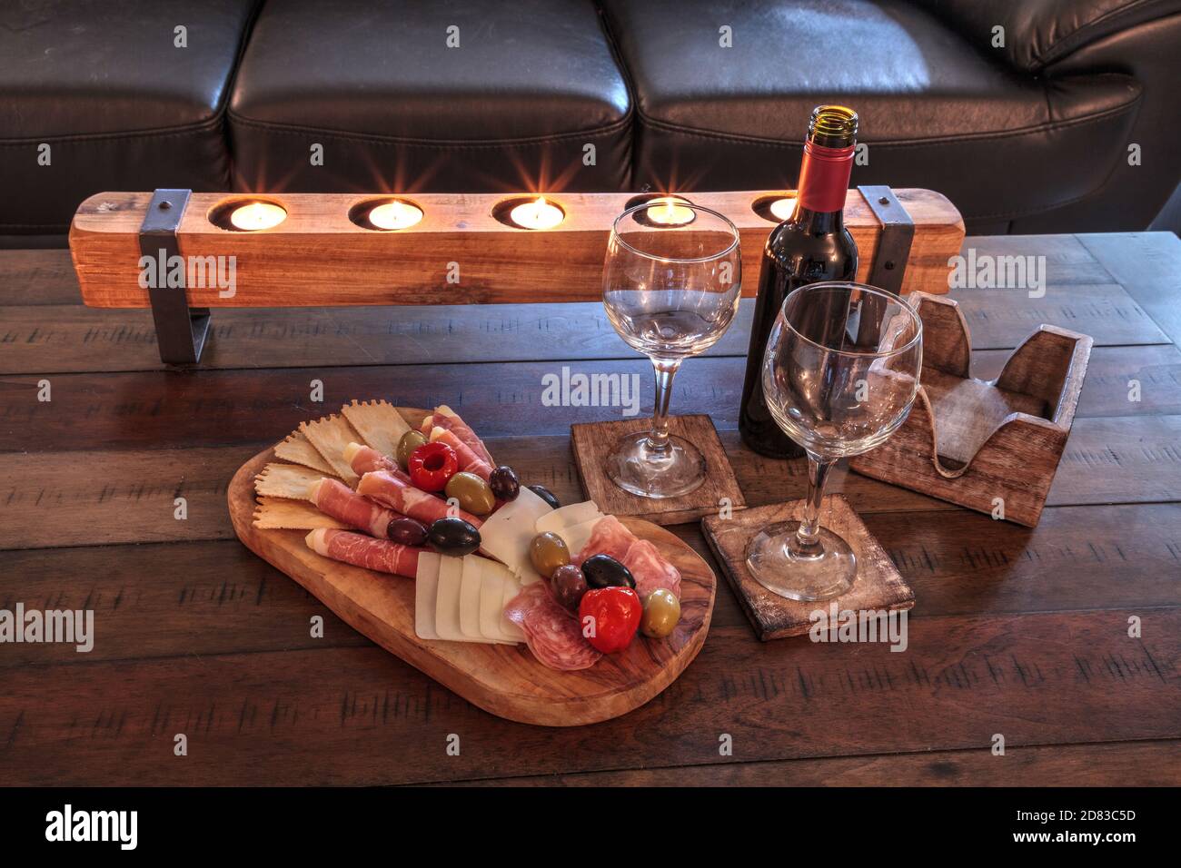 Red wine with Charcuterie board on rustic wood with candles behind a spread of prosciutto panino, mozzarella cheese, Genoa salami, Fontina cheese and Stock Photo