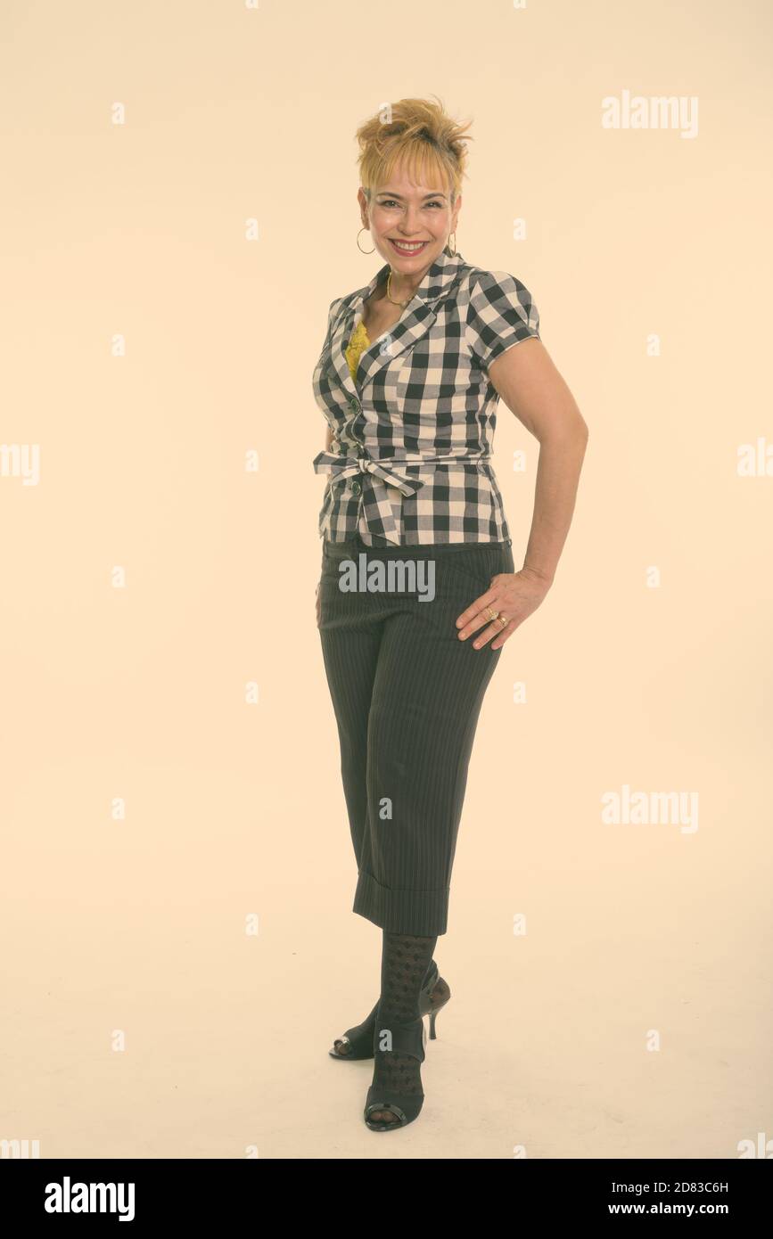 Full body shot of happy senior Asian woman smiling while standing against white background Stock Photo