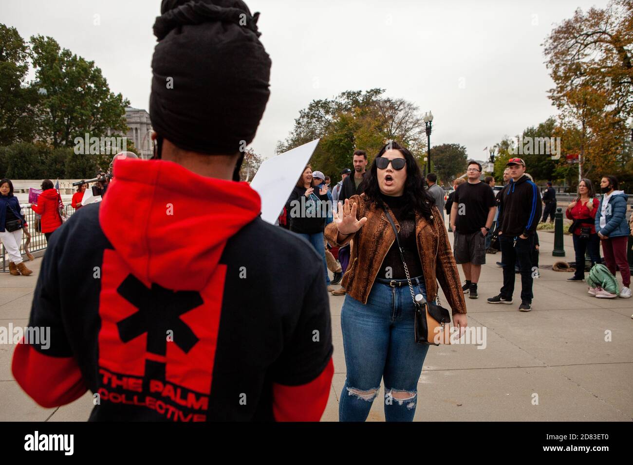 Washington, DC, USA, 26 October,  2020.  Pictured: A Trump supporter verbally attacks a Black woman protesting against the confirmation of Amy Coney Barrett and in favor of reproductive, civil, and women's rights.  She was one of only a few Black people present and was the target of more intense vitriol from Trump supporters than they gave white individuals with similar views.  This was such a problem that a yoiung man had to follow her around, frequently intervening to prevent angry Trump supporters from getting close enough to physically attack her.   Credit: Allison C Bailey/Alamy Live News Stock Photo
