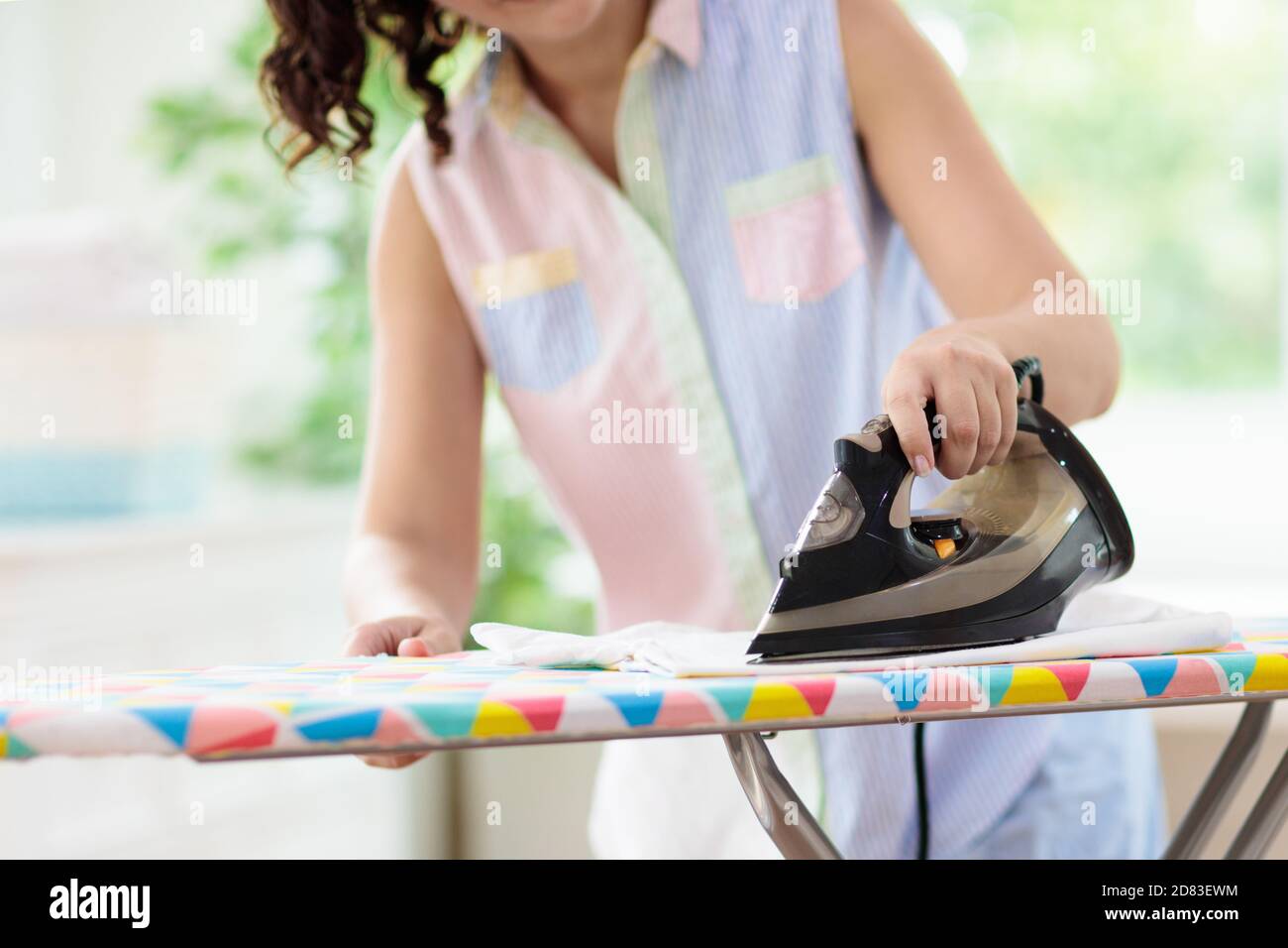Woman ironing clothes. Female folding clothes at iron board. Home chores. Housewife cleaning house. Stock Photo