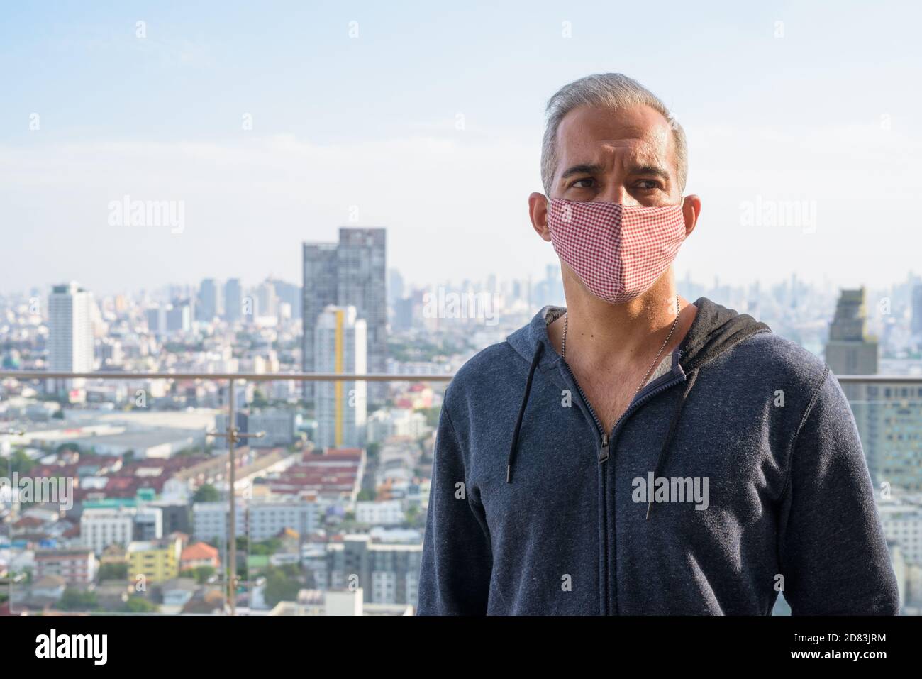 Portrait of Persian man with mask thinking against view of the city Stock Photo